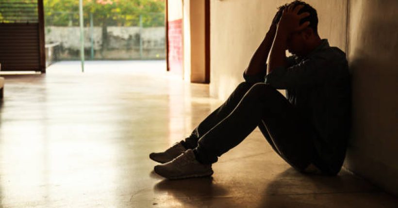 Emotional moment: man sitting holding head in hands, stressed sad young male having mental problems, feeling bad, depressed, disappointed, hopeless. Desperate man in the dark corner needing help.